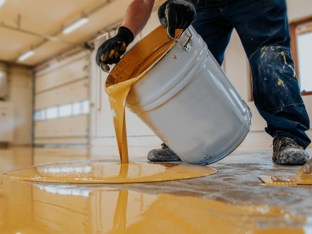 El trabajador aplica resina epoxi amarillo al piso nuevo